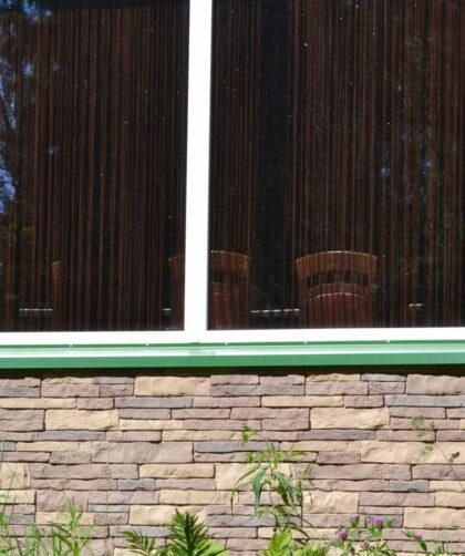 Wandverkleidung außen mit Natursteinplatten in Pastellfarben und Granit Fensterbänken.
