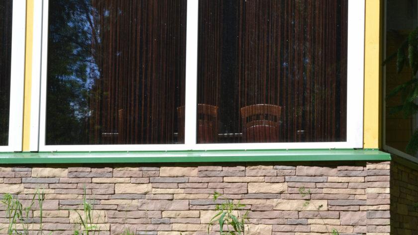 Wandverkleidung außen mit Natursteinplatten in Pastellfarben und Granit Fensterbänken.
