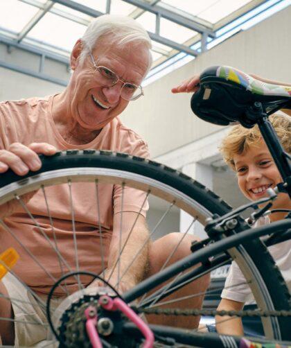 Gut gelaunter Großvater repariert das Fahrrad seines Enkels in der Garage