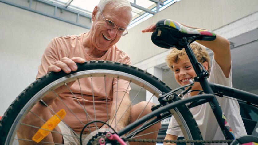 Gut gelaunter Großvater repariert das Fahrrad seines Enkels in der Garage